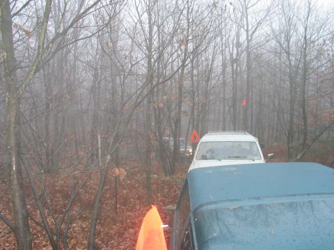 1995 Ford Bronco - Two SUVs navigate a foggy forest trail, marked with orange flags.