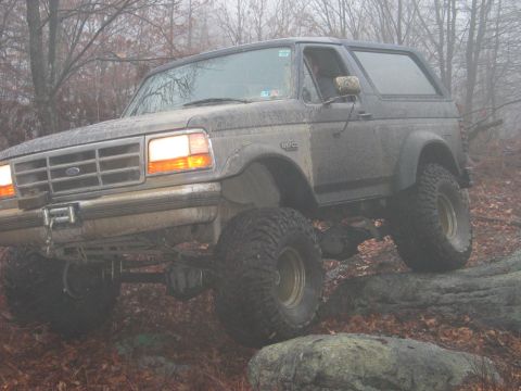 1995 Ford Bronco - A lifted Ford Bronco navigates a challenging off-road course on a foggy day.