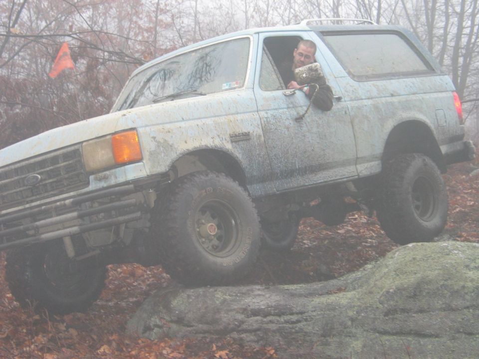 Light blue Ford Bronco navigating rocks, driver visible
