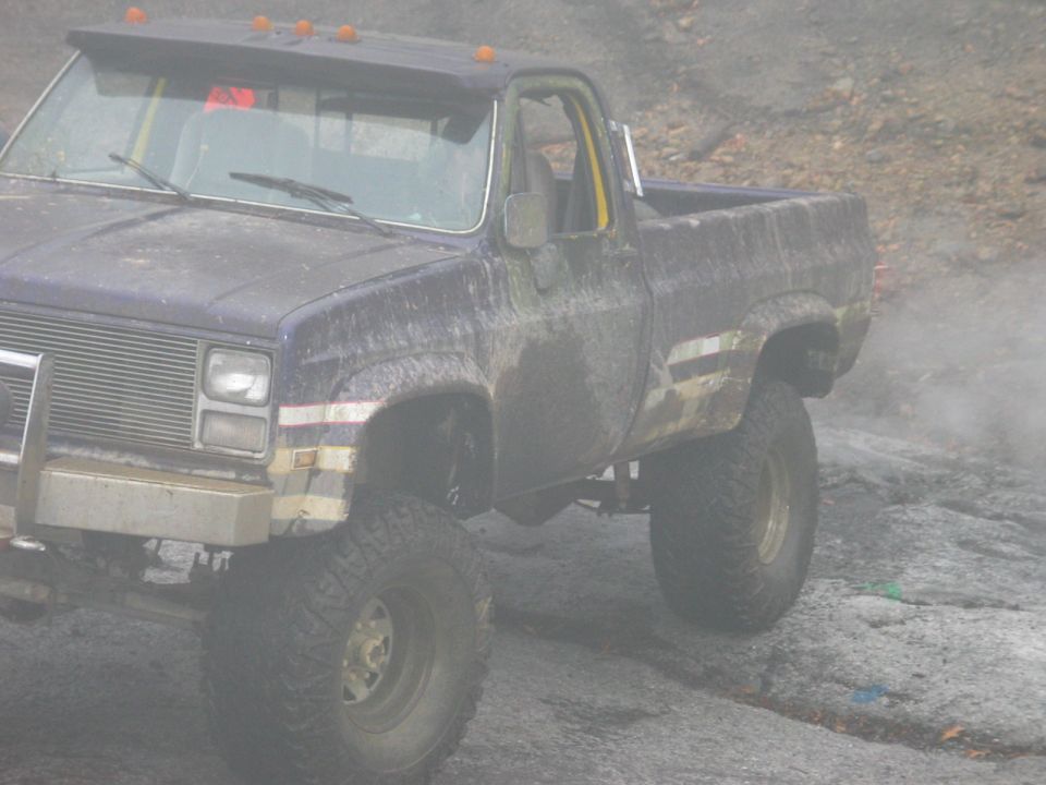 Lifted pickup truck with large tires, off-road modifications, and mud splatter