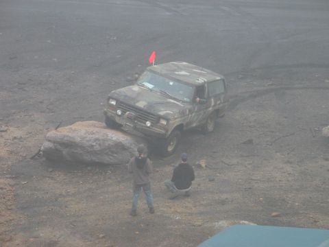 1995 Ford Bronco - A camouflaged Ford Bronco navigates an obstacle course, with two people observing.