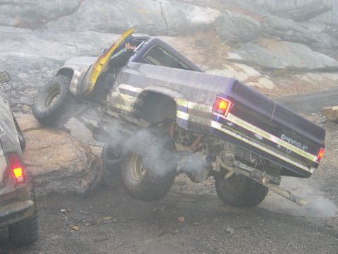 1995 Ford Bronco - This modified Chevrolet pickup truck is navigating a rocky trail, with smoke billowing from its exhaust pipe.