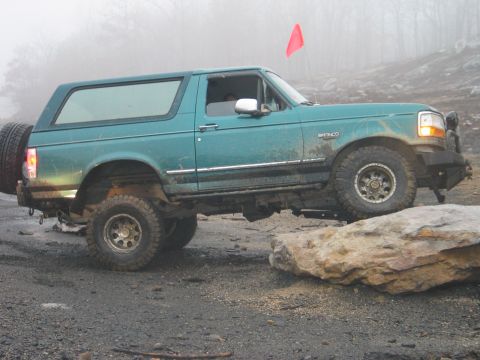 1995 Ford Bronco - 1995 Ford Bronco tackling an obstacle on an off-road trail.