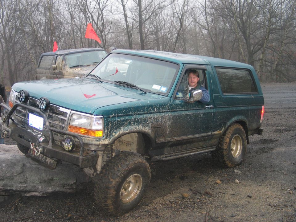Green 1995 Ford Bronco off-roading, front 3/4 view