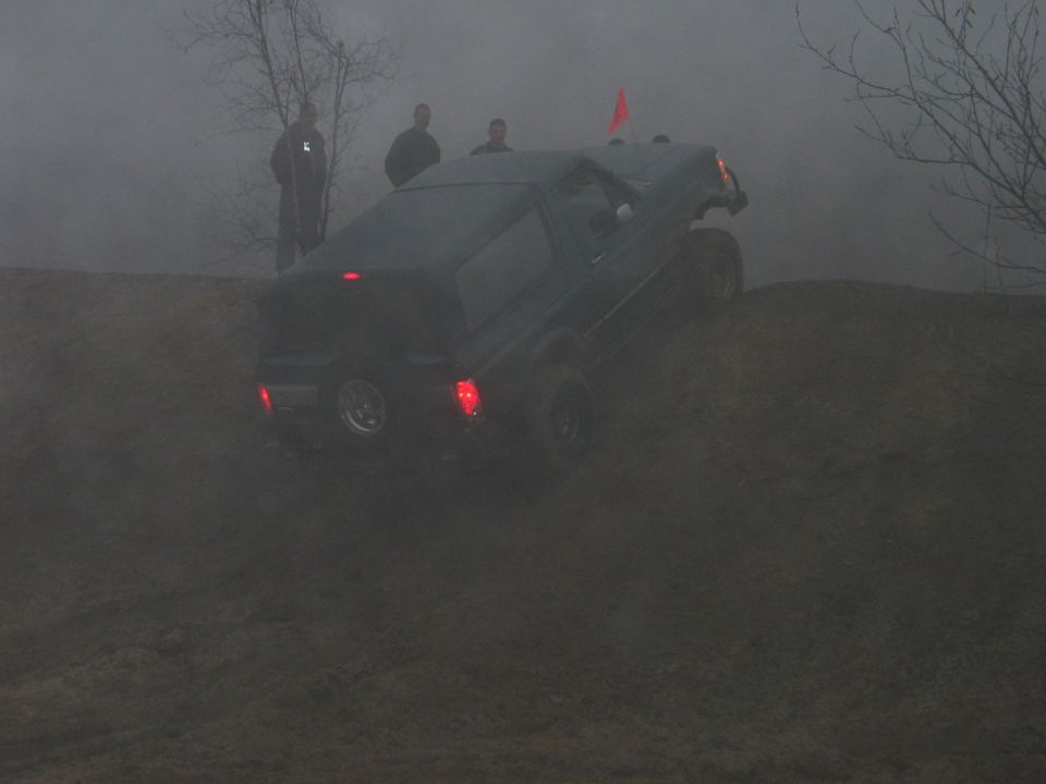 Dark SUV climbing a dirt hill, rear view