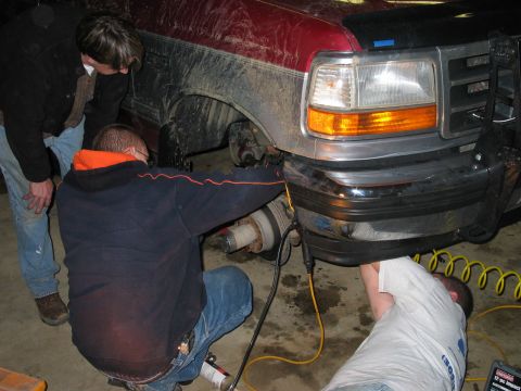 1995 Ford Bronco - Mechanics are working on the suspension of a 1995 Ford Bronco in a garage.