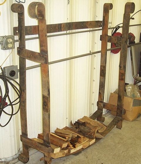 1990 Ford Bronco - A metal firewood rack with logs is shown indoors, next to electrical outlets and cords on a corrugated wall.