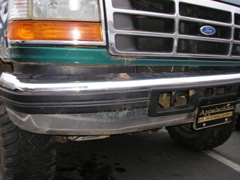 1996 Ford Bronco - A green 1992 Ford Bronco's front end is visible, showing the bumper, grille, and headlight.