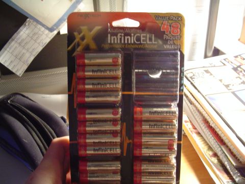 1990 Ford Bronco - A package of 48 Infinicell AA alkaline batteries is held in front of a desk with papers and other items.