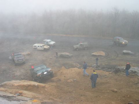 1995 Ford Bronco - Several off-road vehicles navigate a challenging, muddy course amidst a dense fog.