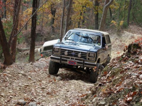 1995 Ford Bronco - A Ford Bronco navigates a rocky off-road trail during autumn.