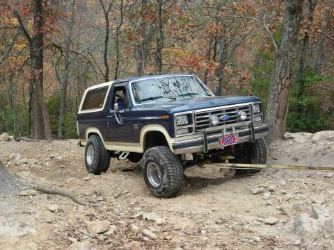 1995 Ford Bronco - A lifted blue and white Ford Bronco navigates a rocky off-road trail during the Uwharrie Bronco Run.
