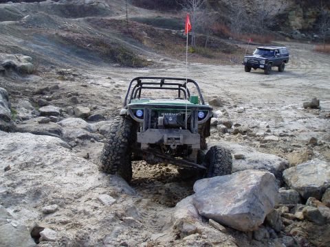 1992 Ford Bronco - A modified off-road vehicle tackles a challenging rocky course, with another SUV visible in the background.