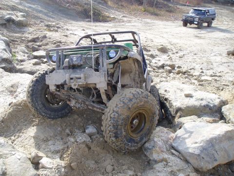 1992 Ford Bronco - A heavily modified off-road buggy tackles a challenging rocky course, with another SUV visible in the background.