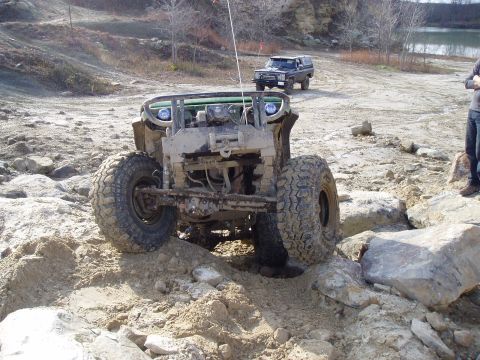 1992 Ford Bronco - Two off-road vehicles traverse a rocky, uneven landscape.