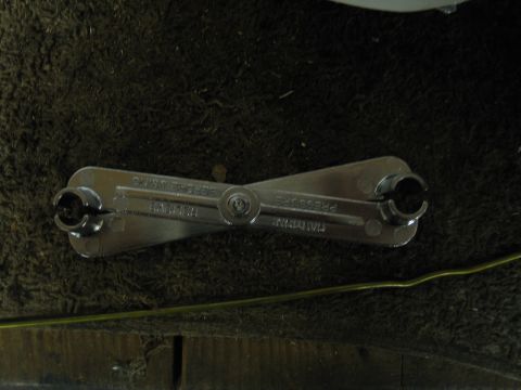 1995 Ford Bronco - A metal tool designed for fuel line disconnection is shown lying on a dark, textured surface.