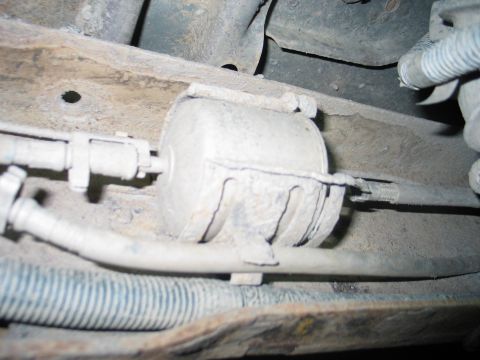1995 Ford Bronco - Underside view of a vehicle's fuel filter assembly, showing hoses and metal lines.