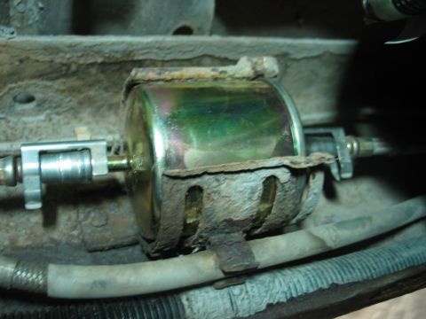 1995 Ford Bronco - Close-up of a corroded fuel filter mounted on a vehicle's undercarriage.