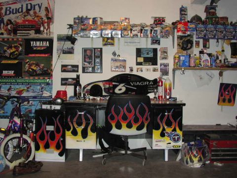 1981 Ford Bronco - A cluttered garage space is decorated with various memorabilia, including racing posters and collectible items.