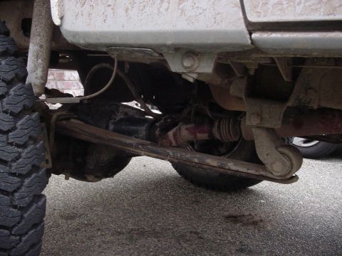 1987 Ford Bronco - Close-up view of a vehicle's rear axle and leaf spring suspension system.