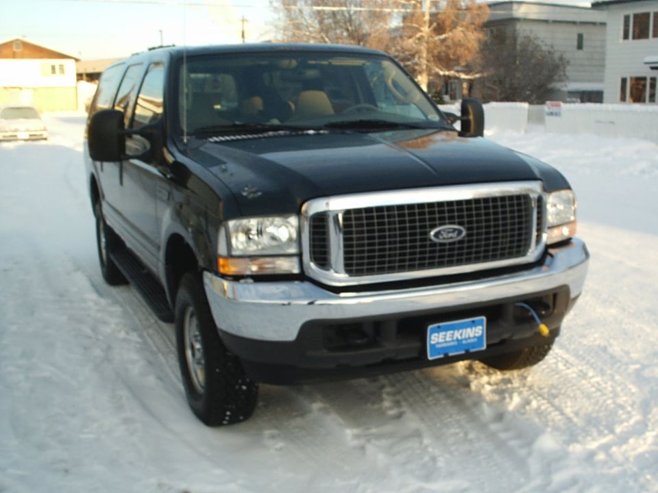 Black Ford Excursion parked in snow. Has a blue license plate that says SEEKINS