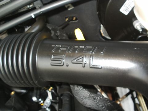 2004 Ford Excursion - Close-up of a TRITON 5.4L engine intake tube, part of a vehicle's engine compartment.
