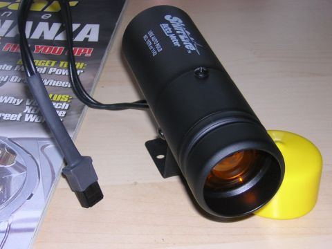1998 Ford Crown Victoria - black cylindrical Splitfire sensor with an attached cable and a yellow protective cap, lying beside a magazine.