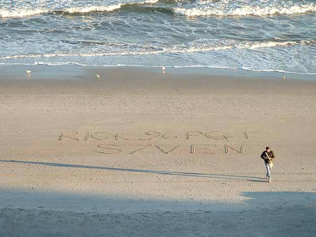 Writing in sand on a beach with a person walking nearby