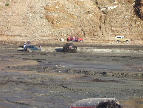 2000 Ford F-450 - Off-road vehicles driving through a mud pit with people observing the action.