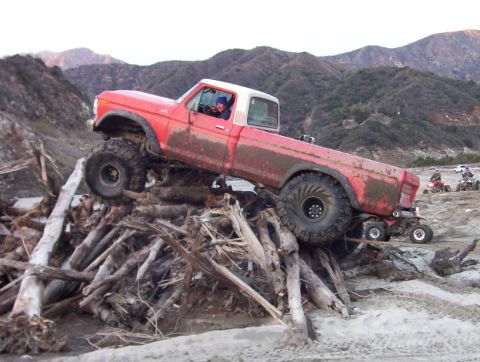 2000 Ford F-450 - Modified pickup truck navigating an obstacle course of logs with ATVs nearby.