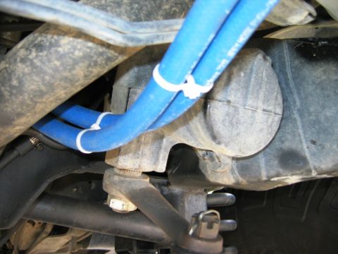 1985 Ford Bronco - Close-up view of the vehicle's undercarriage, focusing on mechanical parts and blue hoses.