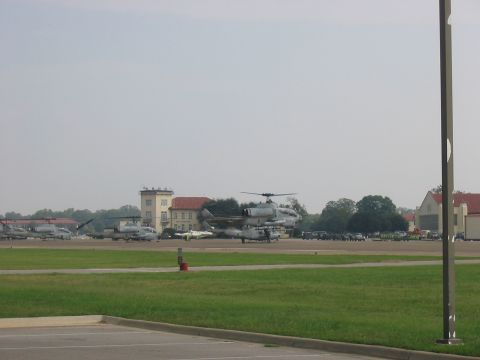 1988 Ford Bronco - Multiple military aircraft, including helicopters and jets, are parked on an airfield with buildings and trees visible.