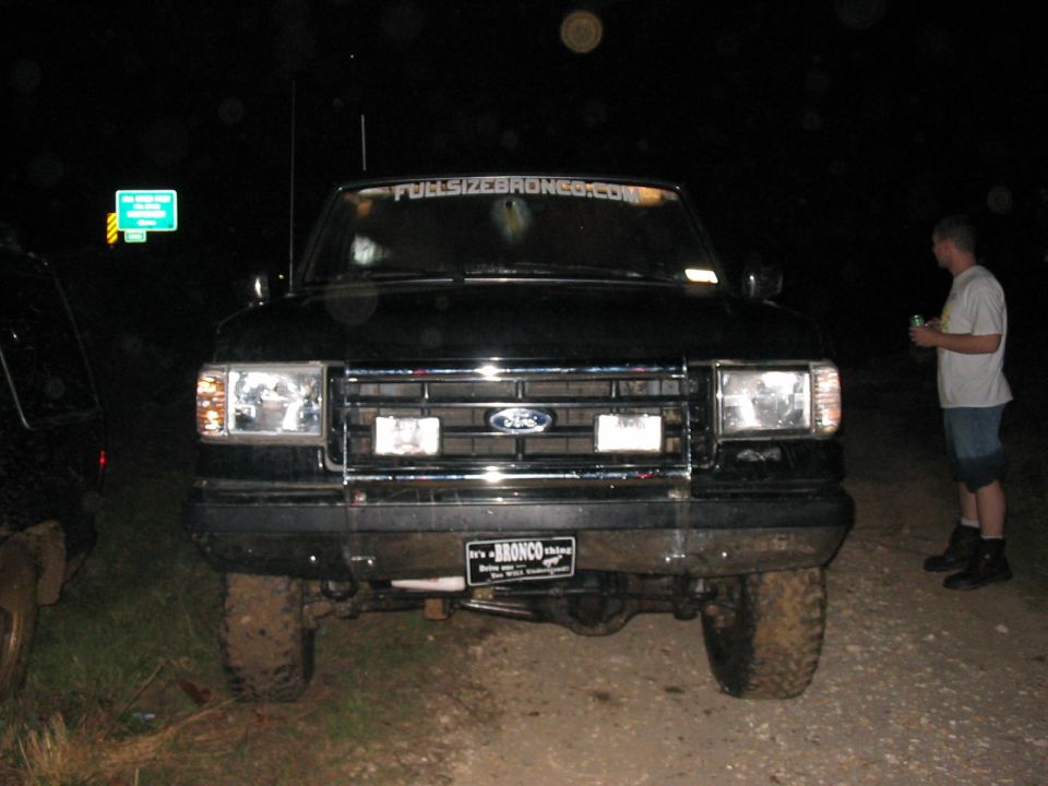 Black Ford Bronco front view, muddy tires, "It's a BRONCO" license plate, "FULLSIZEBRONCO.COM" windshield banner