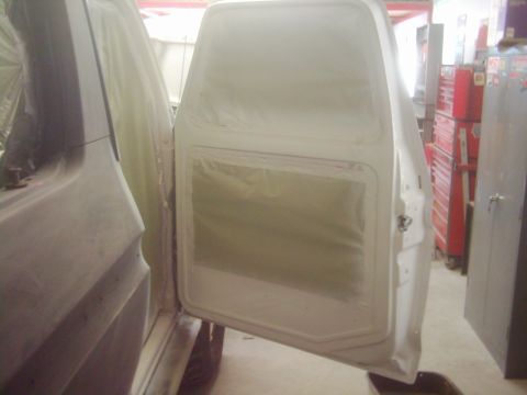 1978 Ford Bronco - Vehicle body panels and door are covered in masking paper, likely for painting.