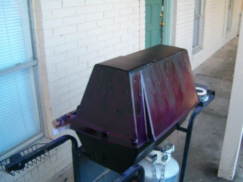 1996 Ford Bronco - Grill with flame decals sits on a stand next to a propane tank outside a building.