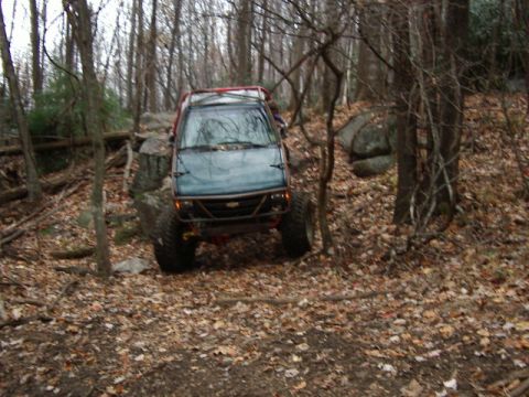 1985 Ford Bronco - This modified off-road vehicle navigates a rocky, wooded trail during an autumn excursion.