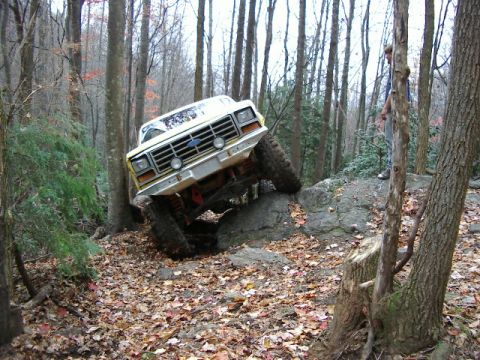 1985 Ford Bronco - This lifted Ford Bronco navigates a rocky, wooded trail, its off-road capabilities.