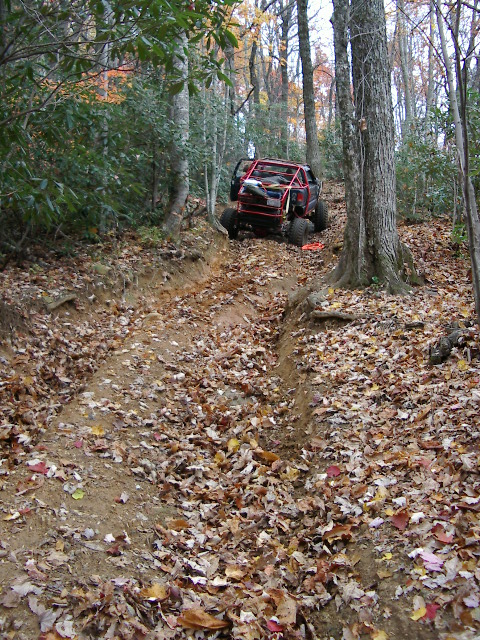 1985 Ford Bronco - A modified off-road vehicle navigates a muddy trail through a wooded area during autumn.