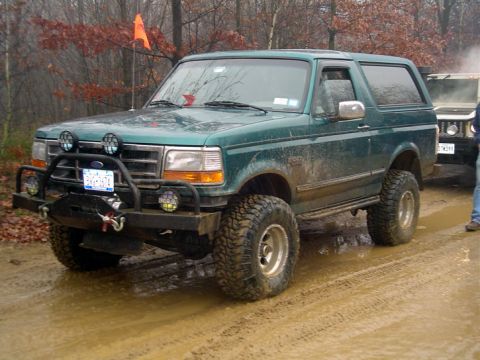 1979 Ford Bronco - Green Ford Bronco on a muddy trail, equipped for off-roading.