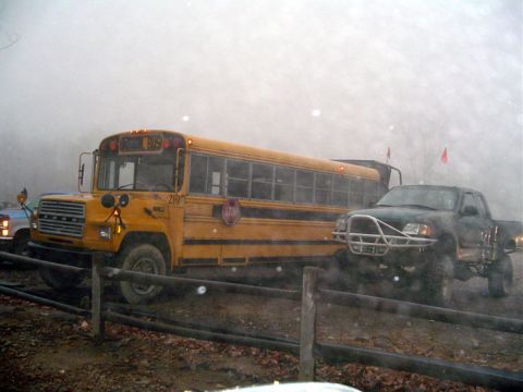 1979 Ford Bronco - A yellow school bus and a modified pickup truck are seen side-by-side in foggy weather.