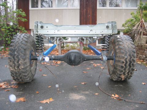 1978 Ford Bronco - Test-fit of a rear coil-spring suspension on a bare frame section: a solid rear axle with coil springs, blue-painted trailing arms, and chu…