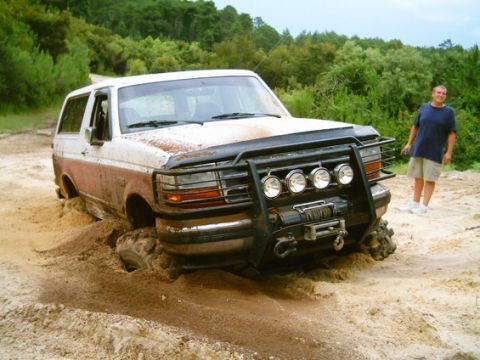 1993 Ford Bronco - Ford Bronco stuck in mud off-road, with a man watching.