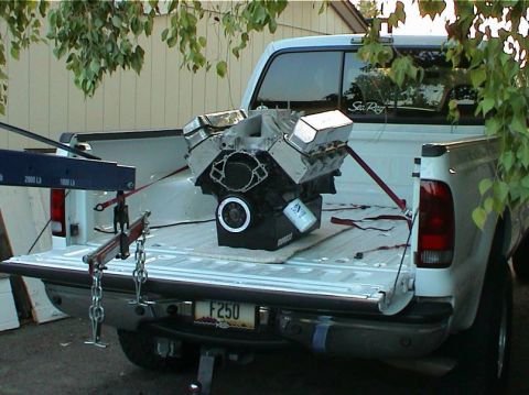 1979 Ford Bronco - A V8 engine is loaded into the bed of a pickup truck for transport.