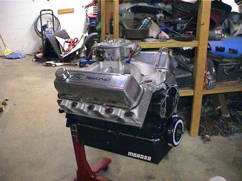 1979 Ford Bronco - A Ford Racing V8 engine, likely a performance build, is displayed on a red engine stand in a garage setting.