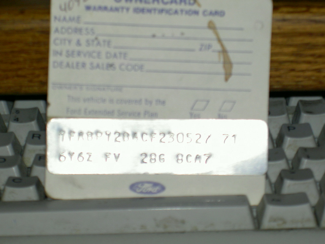 Warranty identification card with VIN and license plate details, resting on a keyboard