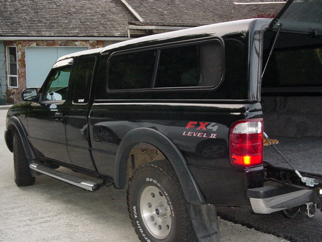 Black Ford Ranger pickup with bed cap, FX4 Level II decals, rear three-quarter view in driveway