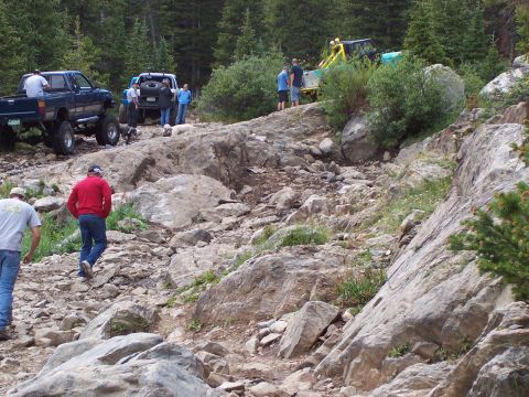 1991 Ford Bronco - Off-road vehicles tackle a challenging rocky path in a mountainous, wooded area.