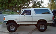 1988 Ford Bronco - This white SUV is lifted with large tires and seen from the side.