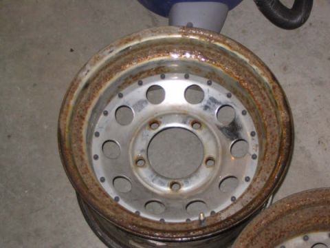 1987 Ford Bronco - A close-up view of a heavily rusted wheel rim, showing its circular design and bolt pattern.