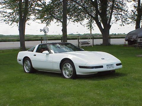 1994 Chevrolet Corvette - A white 1994 Chevrolet Corvette coupe is parked on a grassy lawn with trees in the background.